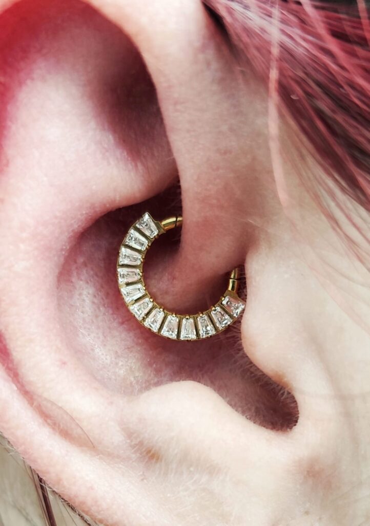 Piercing daith con joyería dorada realizado por Anaís López en Madrid